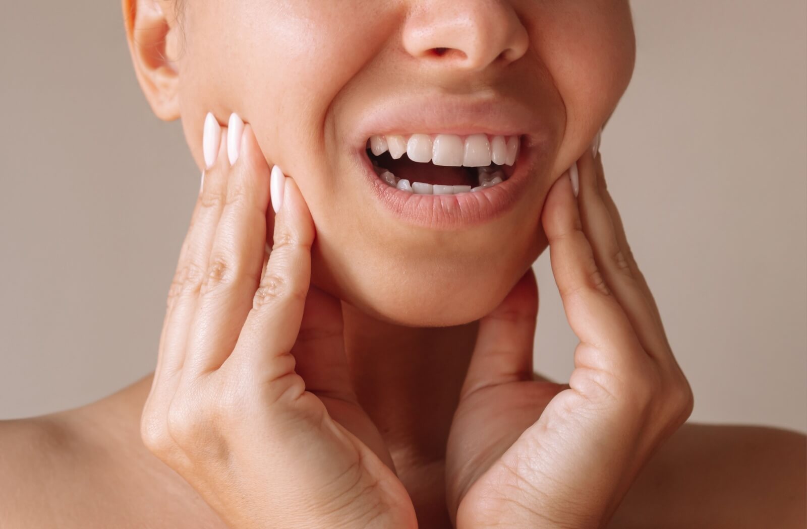Close-up of a person holding their fingers to their jaw in discomfort.