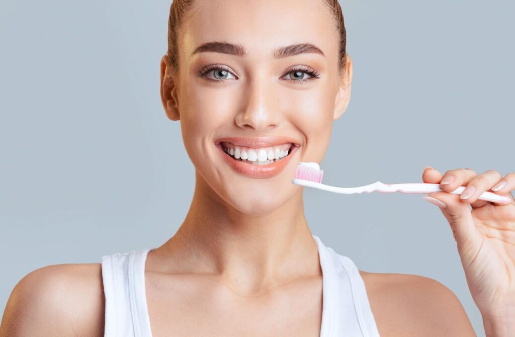 Smiling while holding a toothbrush with toothpaste for a daily dental routine.